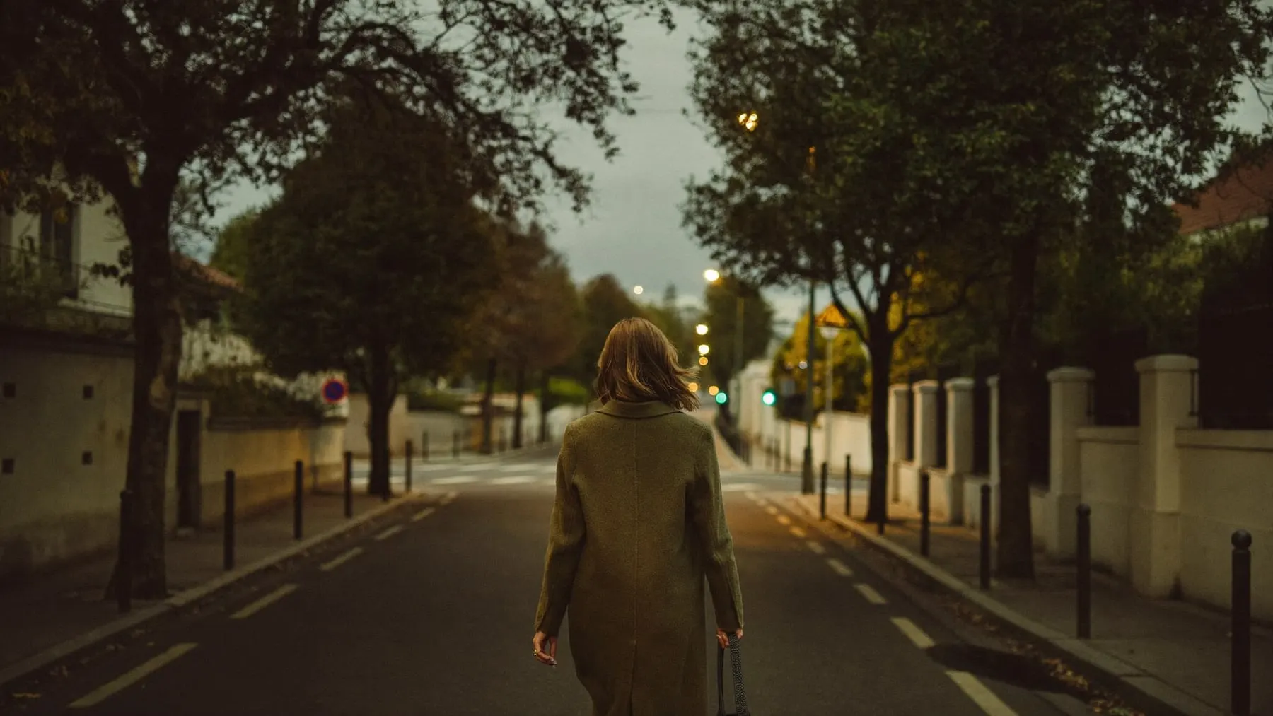 A woman walking away down a street at dusk